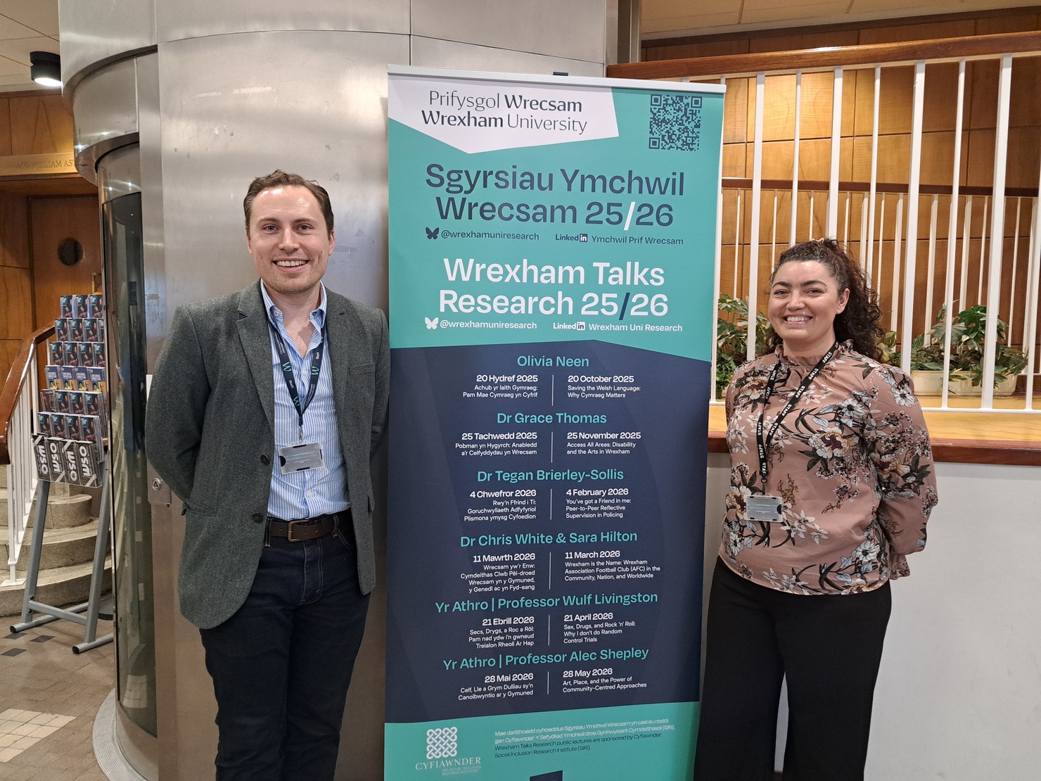 Two staff members standing near an advertising banner