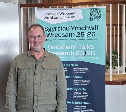 Researcher stood in front of an advertising banner