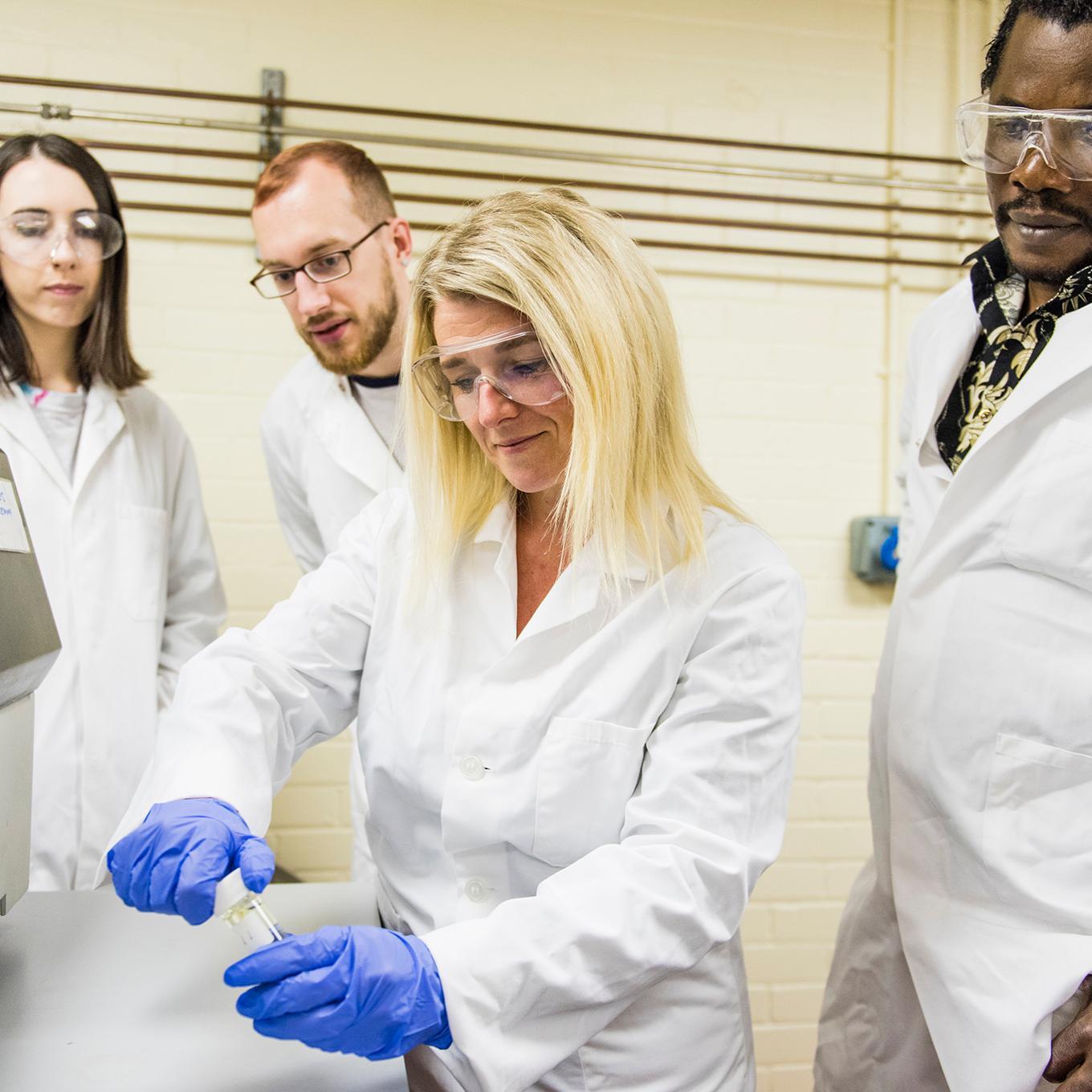 A student uses laboratory equipment while other students observe