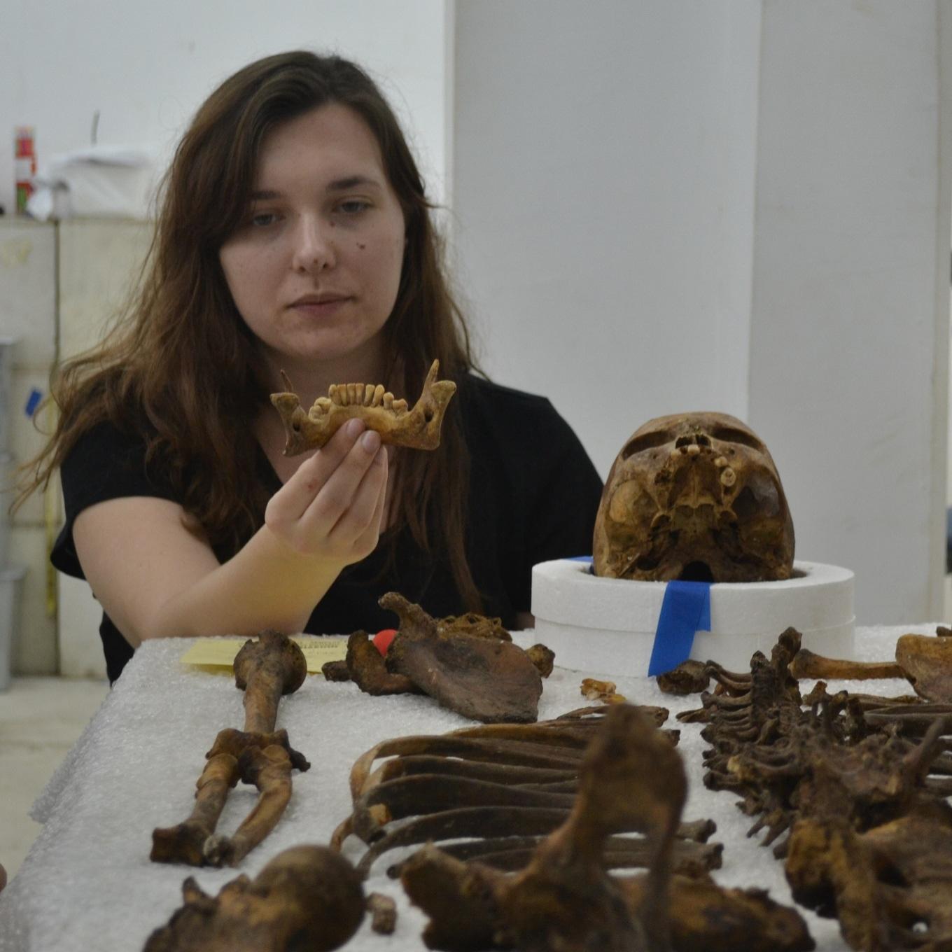 A forensics student examining a skeleton's remains