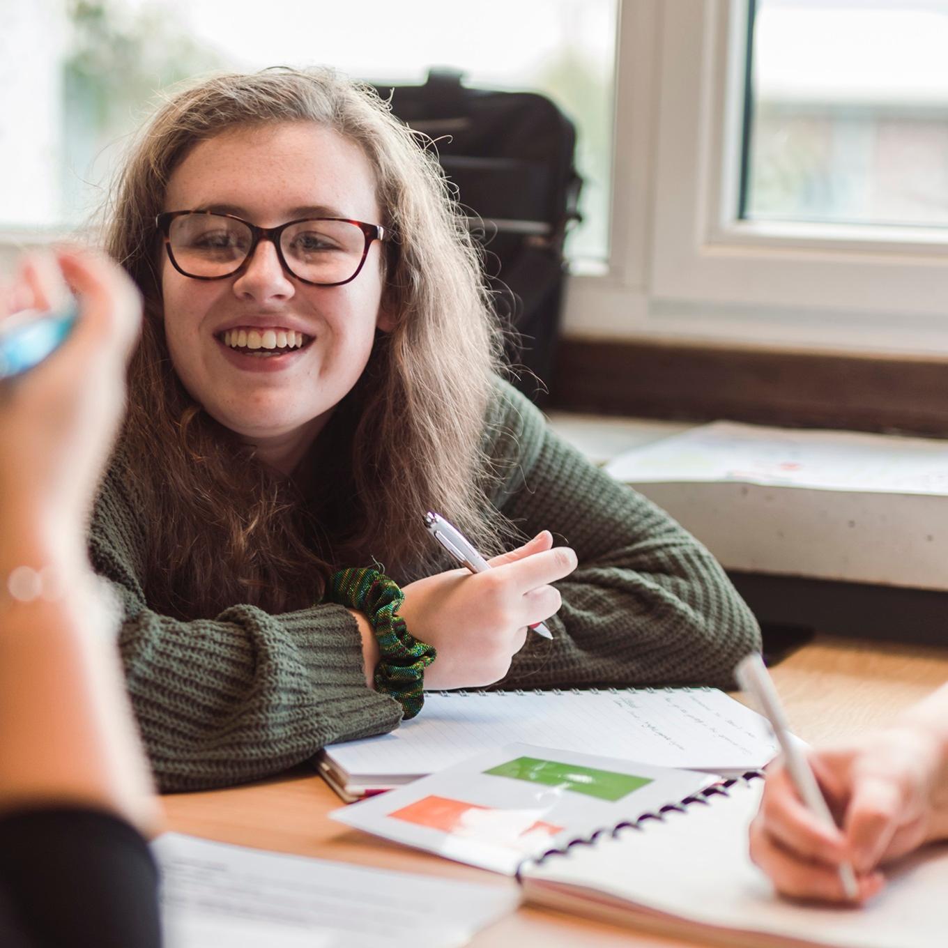 A student working at a desk with classmates