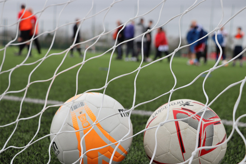 Two footballs in a goal net