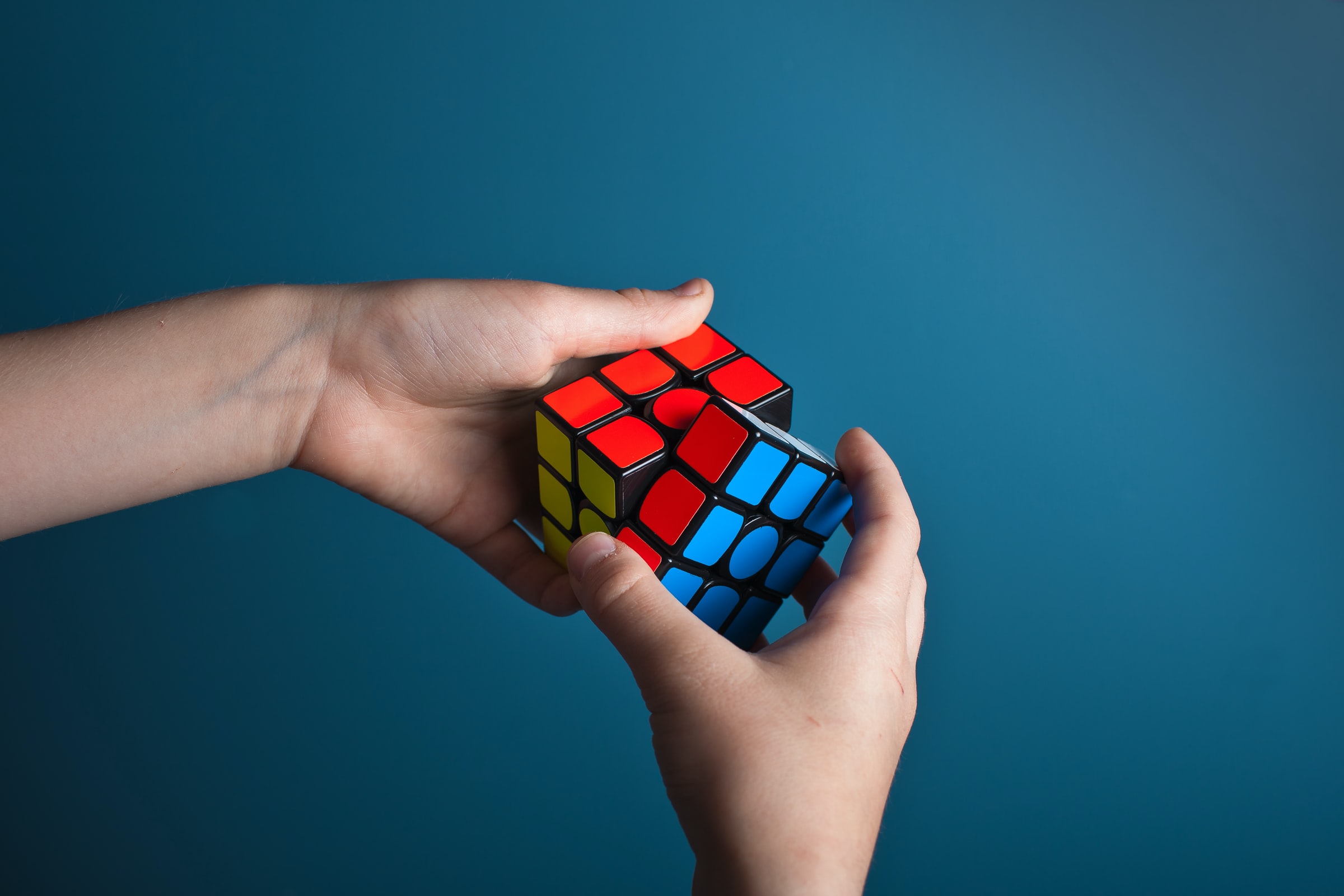 hands playing rubiks cube